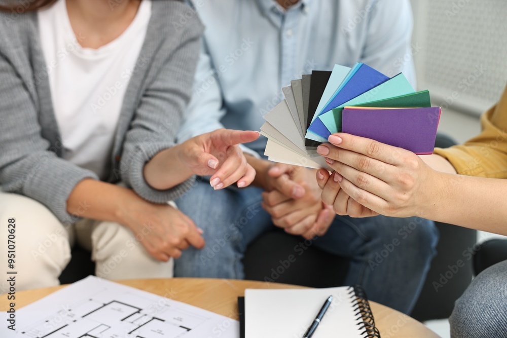 Poster designer discussing project with clients at table indoors, closeup