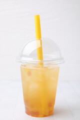 Fototapeta premium Tasty bubble tea in plastic cup on white tiled table against light background