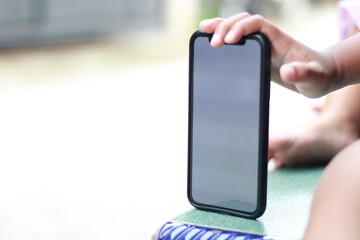 Child's hand reaching for a black smartphone.