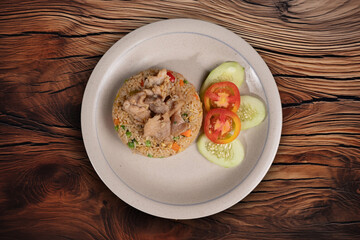 Savor the taste of this perfectly seasoned pork fried rice, served with fresh cucumber and tomato slices.