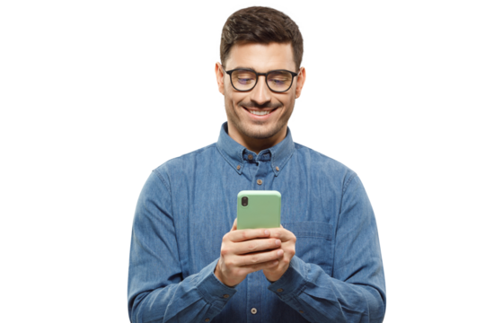 Young man wearing blue shirt and glasses, holding his phone and exchanging messages with frieends with smile