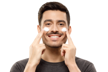 Young smiling man feeling happy about regular beauty routine, applying face cream on cheeks with fingers, feeling relaxed