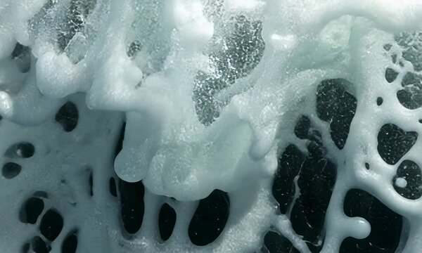 Close-up view of soapy water with bubbles and foam, showing various shades white grey.