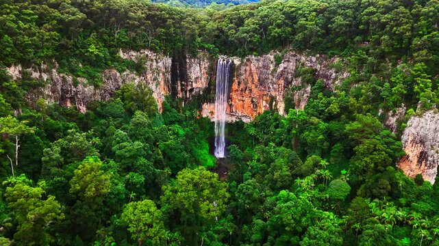 Close up to huge waterfall in the forest. Cloudy day. Drone footage