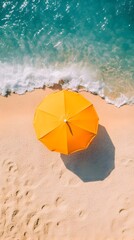 Naklejka premium Aerial View of Vibrant Yellow Sun Umbrella on a Pristine Summer Beach with Turquoise Ocean Waves