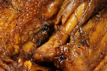 A plate of savory dishes including sweet grilled chicken with a dark brown color, fried tofu and tempeh, and crispy crumbs, served on a white plate against a dark background.