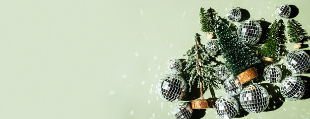 Mini Christmas trees and disco balls on green background. Festive holiday decoration concept.