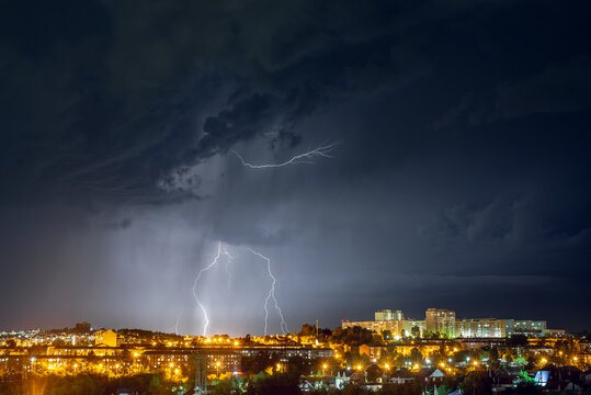 Lightning strikes in the night city among the menacing black clouds. Storm and thunderstorm