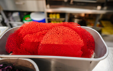 Red lace-like food in metallic container on kitchen counter