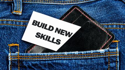 Business, education build new skills concept. Copy space. Concept word BUILD NEW SKILLS on a white card peeking out of a business card holder in a jeans pocket