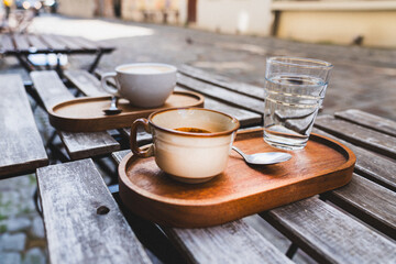 Coffee cup on outdoor garden restaurant. City street lifestyle. Natural wood colors.