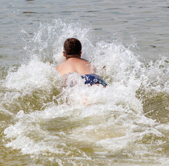 Fototapeta premium A boy runs through the water of the sea and jumps into the water