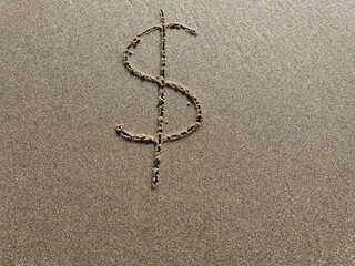 On the beach in the sand is carved a dollar symbol