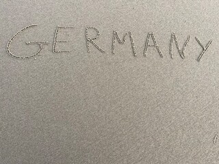 on the beach is carved with letters in the smooth sand the writing Germany