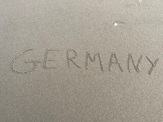on the beach is carved with letters in the smooth sand the writing Germany