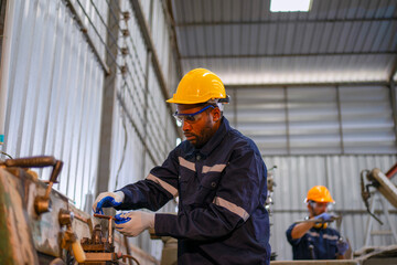 Blue collar workers at machine shop with welding robot arm.