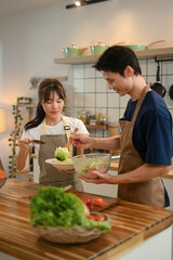 Young couple wearing aprons enjoying their cooking time in a modern kitchen. Healthy and nutritious lifestyle concept