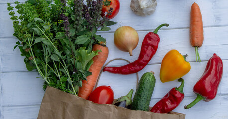 fresh vegetables and paper bag on white wooden background. Selective focus