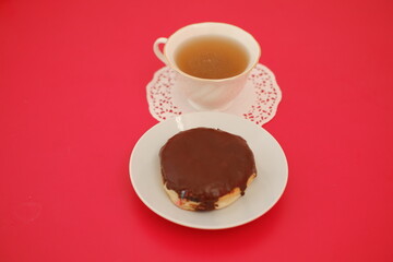 chocolate donut and cup of tea on the red table