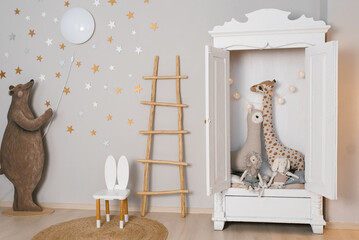 White dresser with a giraffe stuffed animal inside. Children room is decorated with stars and a...