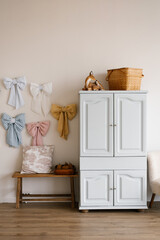 White dresser with bows hanging on the wall and straw basket on top in cozy and welcoming...