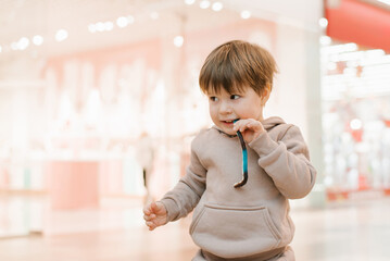 Child boy stands in a store with a jelly candy in his mouth