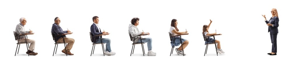 Teacher standing in front of young and older people in school chairs