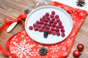 Funny Christmas tree shaped raspberry berry on plate, red sock on wooden background for kids children breakfast. xmas food with new year decorations