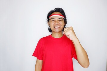 Portrait of an Indonesian man with long hair with a headband and red shirt celebrating Indonesian Independence Day with high nationalism on an isolated white background