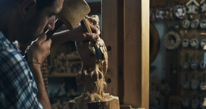 Super slow motion close up of artisan carpenter is working piece of wood with chisel for crafting wood artistic sculpting items in his workshop studio at 1000 fps.