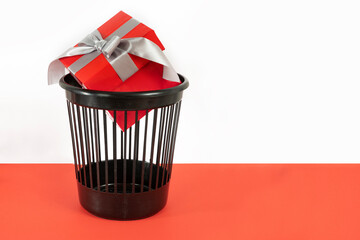 Gift box in trash bin or waste bucket. Rejected bad gift concept