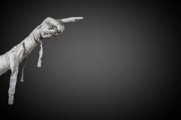 Mummy's hand wrapped in a bandage creepily pointing on isolated background. The hand of the mummy monster for Halloween horror concept