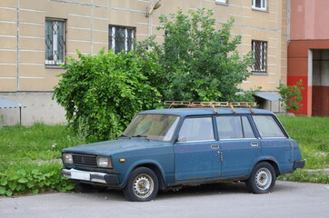 Fototapeta premium An old dark-green Soviet car in the courtyard of a residential building, Bolshevikov Avenue, St. Petersburg, Russia, June 19, 2024