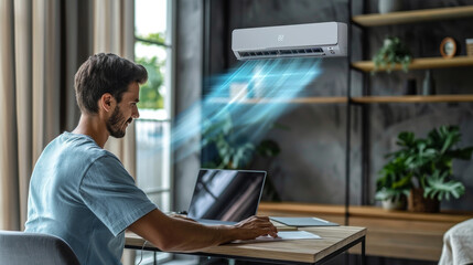Man working on a laptop in a modern home office, enjoying a cool breeze from an air conditioner