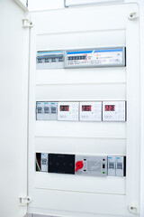 Close-up of a modern electrical control panel with digital voltage displays and circuit breakers.