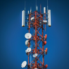 Telecommunication tower with white antenna. Blue sky in background. Mobile phone communication antenna tower. Network 