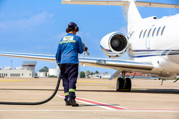 Sustainable Aviation Fuel (SAF) Technician refueling private jet with SAF at the airport.