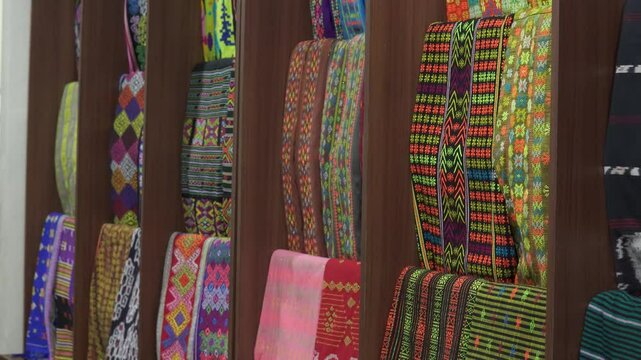 A variety of Indonesian traditional colorful fabrics called Kain Tenun are displayed in a store.