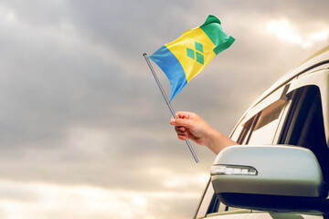 Waving the Saint Vincent flag against the sunrise or sunset from a car driving along a country...
