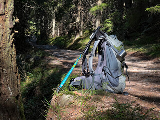 Travel camping backpack near the forest trail. Slightly used tourist bag is standing near the path. Hiking concept.
