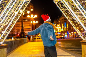 African man raising arms gazing Christmas city lights at night