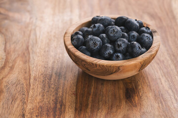 Fresh blueberries in wood bowl on table slightly toned