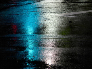 Tokyo, Japan -August 31, 2024: Reflection of Traffic light  on a wet road at night