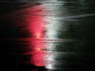Tokyo, Japan -August 31, 2024: Reflection of Traffic light  on a wet road at night