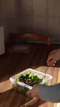 Woman hands stirring a tupper salad in rustic kitchen. Real people. Healthy food. Vertical footage.