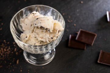 white creamy ice cream with pieces and crumbs of chocolate in a glass bowl