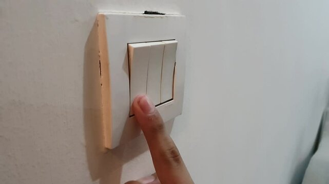 A boy's hand pressing on-off button in an electic socket at home. A vintage design of electricity. 