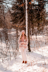 A young attractive girl is walking in the the forest and enjoying the first snow