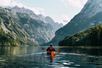 Man is kayaking on a beautiful lake surrounded by mountains, enjoying the peace and tranquility of nature