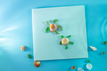 Artistic arrangement of seashell and sea glass pieces on blue background, forming a turtle shape. Seashell as the turtle shell, sea glass as head and limbs, creativity with natural elements,